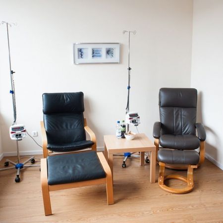 Zwei bequeme Behandlungsstühle in einem hellen Therapieraum mit Infusionsständern